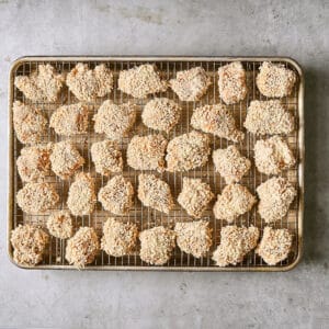 Panko-breaded chicken pieces on a wire rack set in a rimmed baking sheet.
