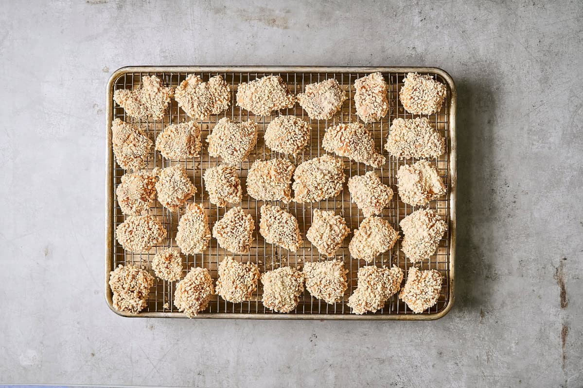 Panko-breaded chicken pieces on a wire rack set in a rimmed baking sheet.