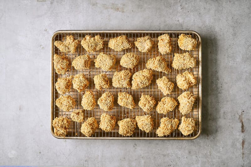 baked Panko-breaded chicken pieces on a wire rack set in a rimmed baking sheet.