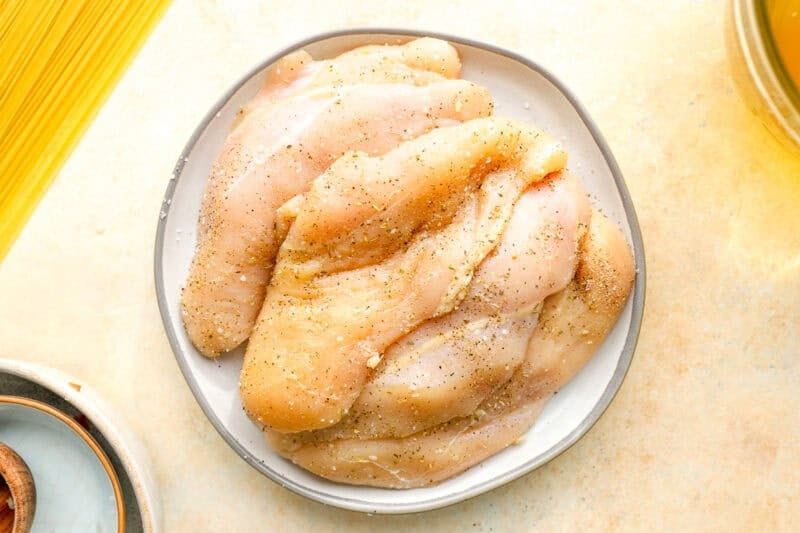 seasoned thin-sliced chicken breasts on a plate.