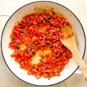 warming bruschetta in a pan with a wooden spoon.