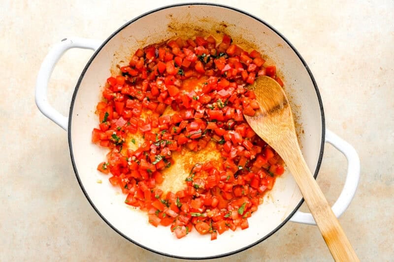 warming bruschetta in a pan with a wooden spoon.