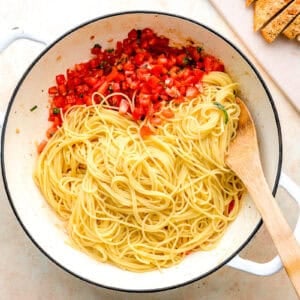 tossing angel hair pasta with bruschetta in a pan.