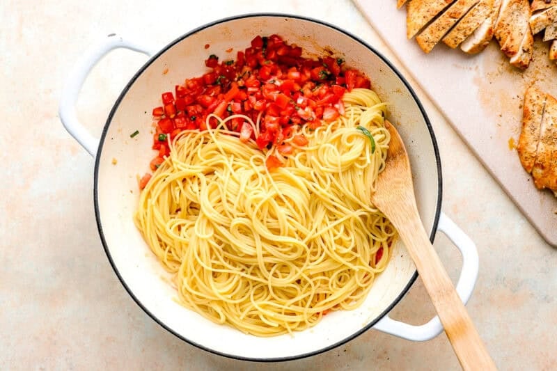 tossing angel hair pasta with bruschetta in a pan.