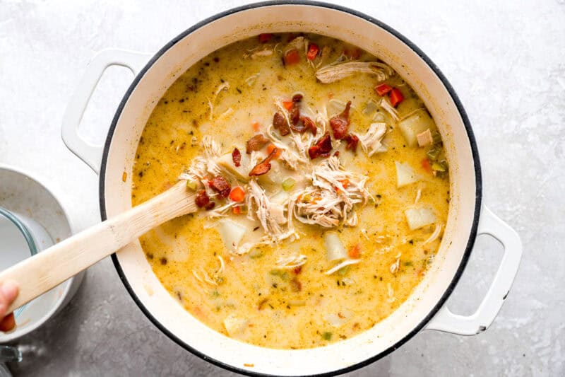 creamy chicken and potato soup in a dutch oven with bacon.