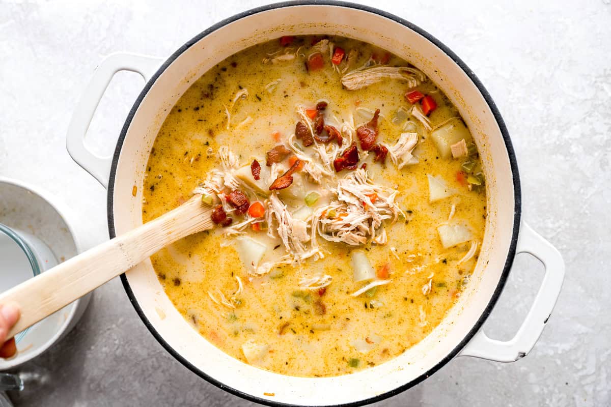 creamy chicken and potato soup in a dutch oven with bacon.
