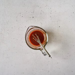 thick korean bbq chicken sauce in a glass bowl with a whisk.