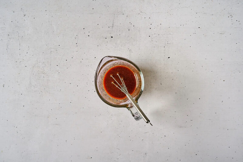 thick korean bbq chicken sauce in a glass bowl with a whisk.