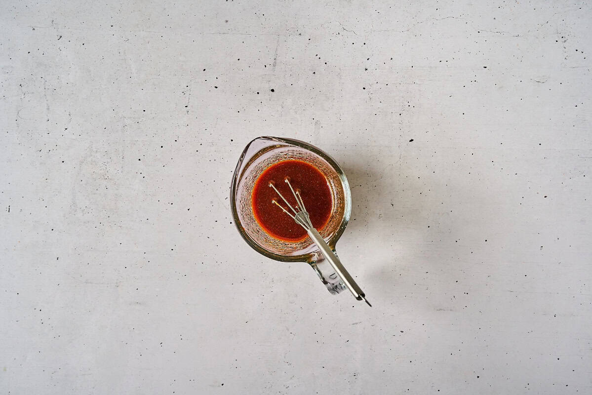 thick korean bbq salad dressing in a glass bowl with a whisk.