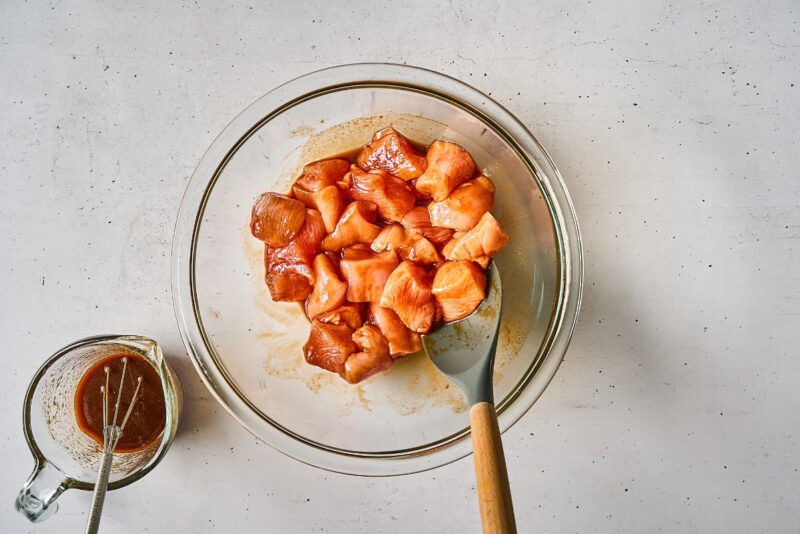 raw cubed chicken breast tossed in thick korean bbq sauce in a bowl.