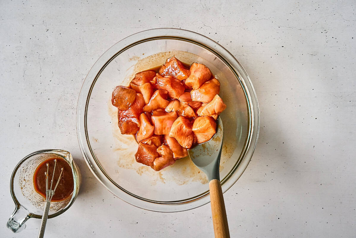 raw cubed chicken breast tossed in thick korean bbq sauce in a bowl.