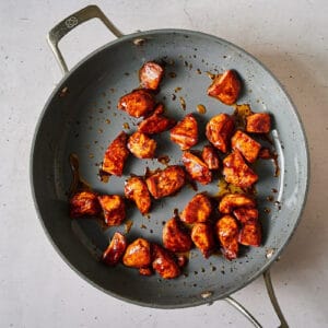 sticky glazed korean bbq chicken breast pieces in a pan.