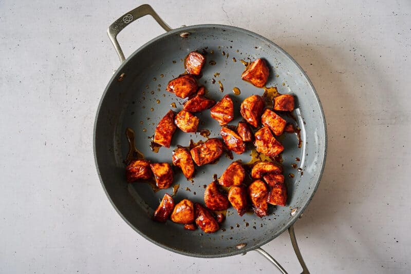 sticky glazed korean bbq chicken breast pieces in a pan.