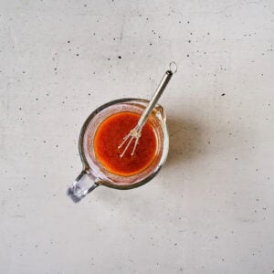 thinned korean bbq chicken salad dressing in a glass bowl with a whisk.