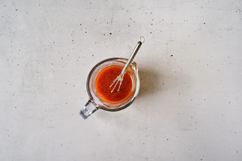 thinned korean bbq chicken salad dressing in a glass bowl with a whisk.
