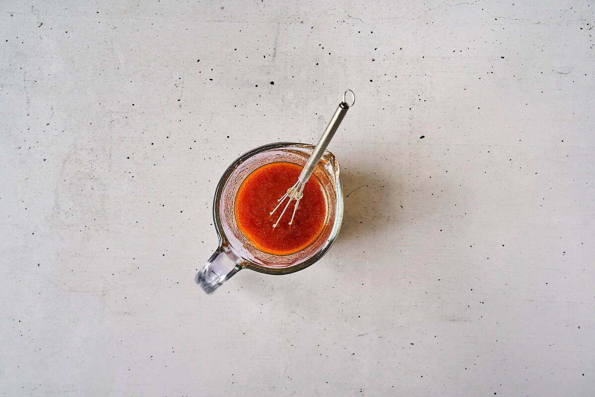 thinned korean bbq chicken salad dressing in a glass bowl with a whisk.