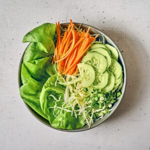 butter lettuce, cabbage, carrots, cucumbers, and green onions in a bowl for Korean salad.