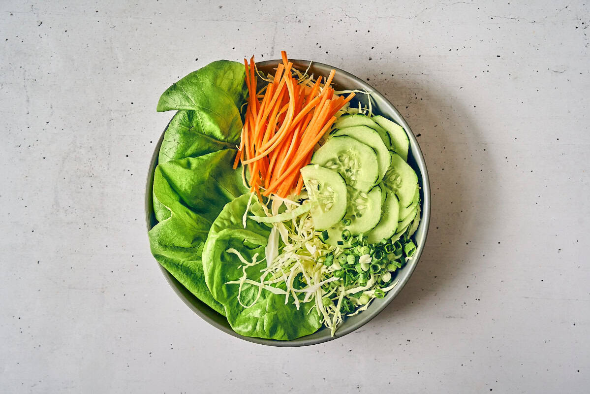 butter lettuce, cabbage, carrots, cucumbers, and green onions in a bowl for Korean salad.