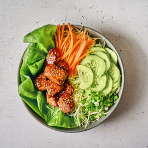 a serving of korean bbq glazed chicken bites over salad.
