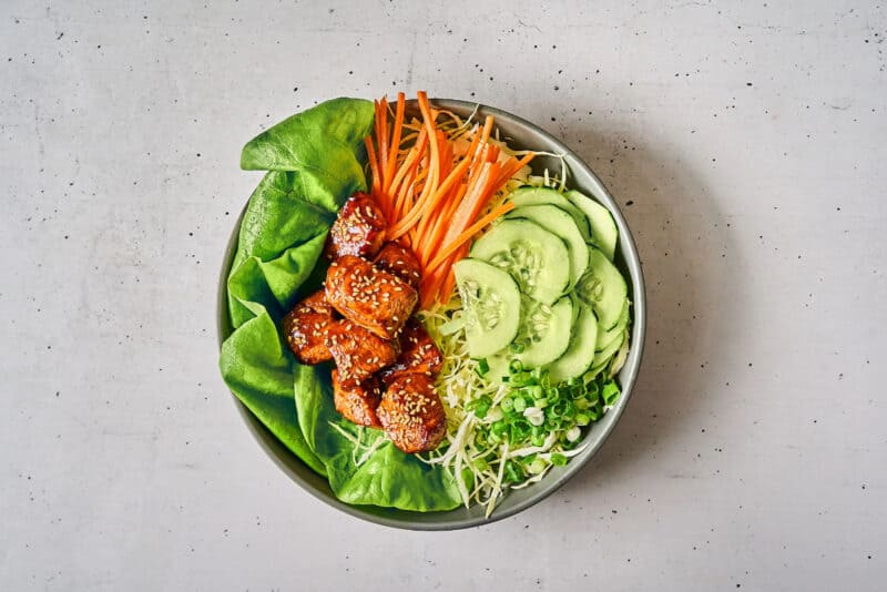 a serving of korean bbq glazed chicken bites over salad.