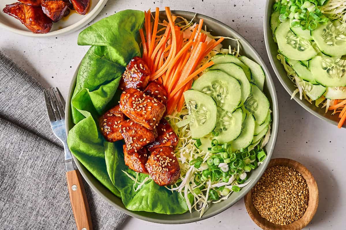 a serving of korean bbq glazed chicken bites over salad.
