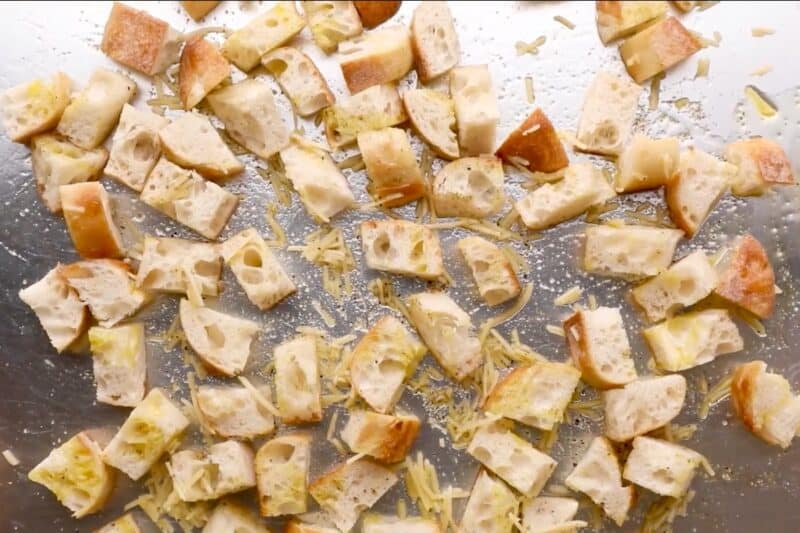 Seasoned cubes of bread on a baking sheet.