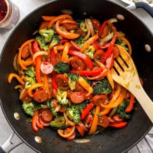 Chicken sausage stir fry being stirred in a skillet.