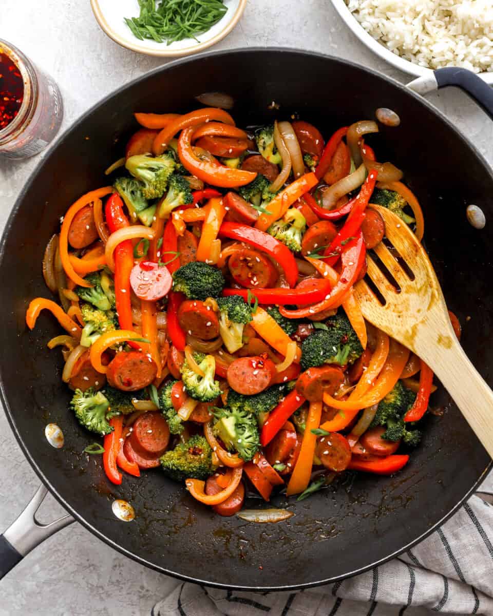Chicken sausage stir fry being stirred in a skillet.
