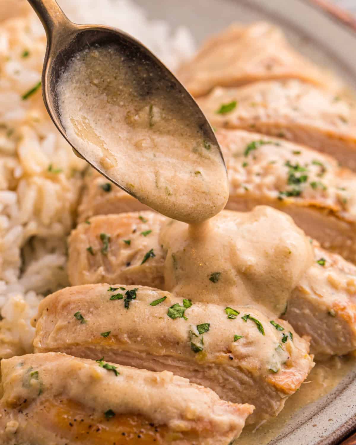 Lime coconut milk sauce being spooned over a sliced chicken breast.