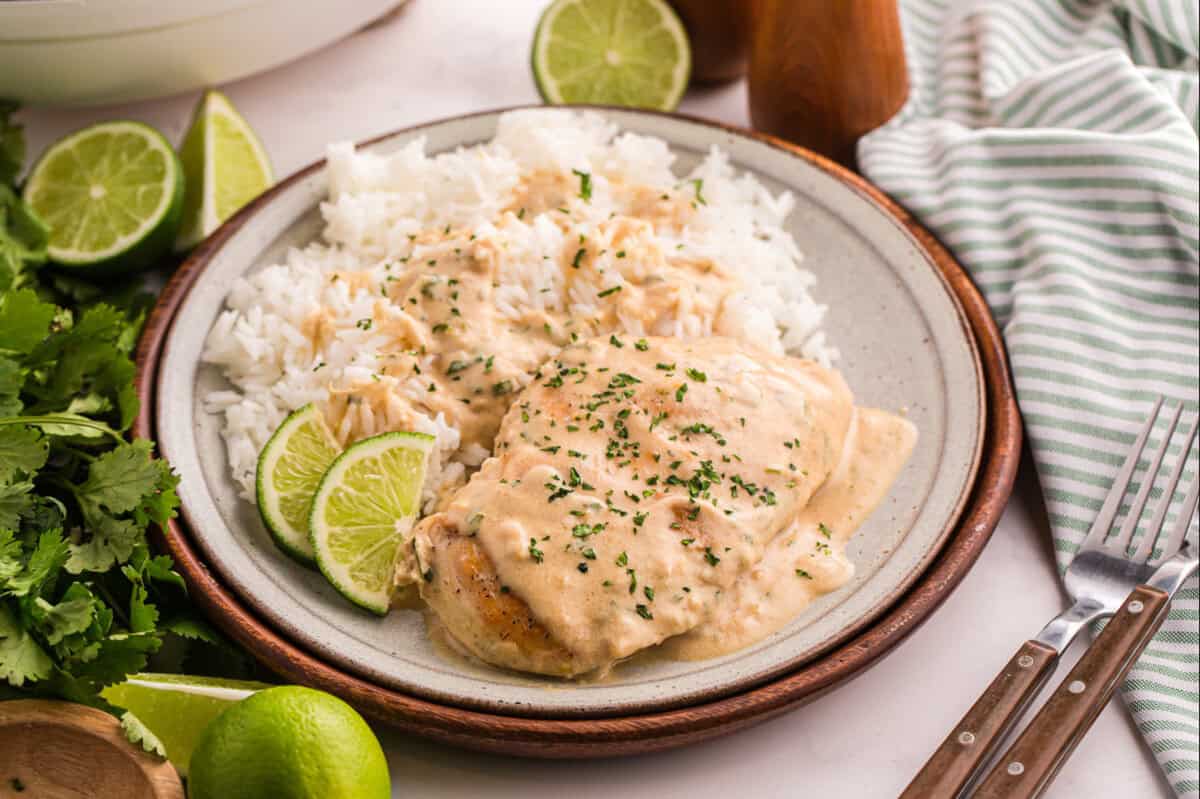 Creamy coconut lime chicken served with rice and lime wedges.