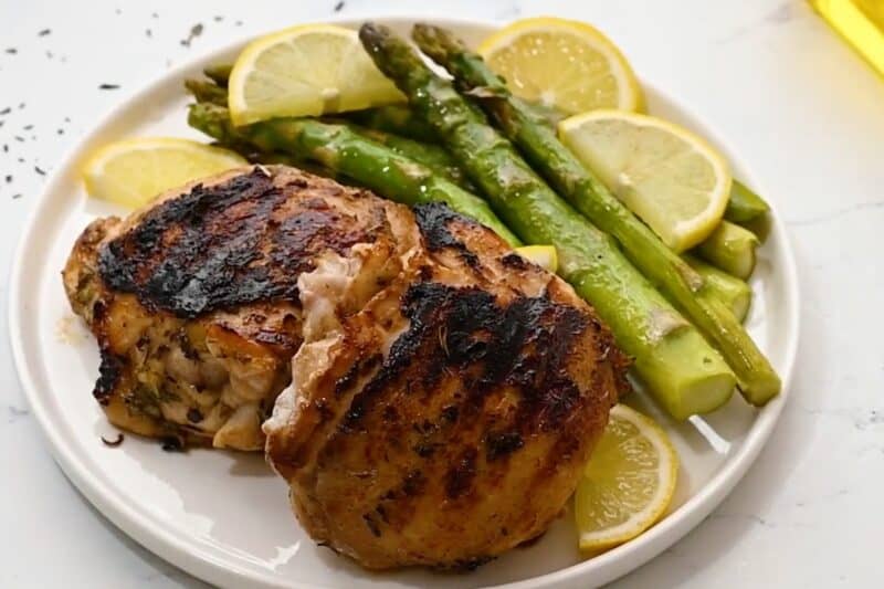 Grilled chicken thighs served on a plate with asparagus.