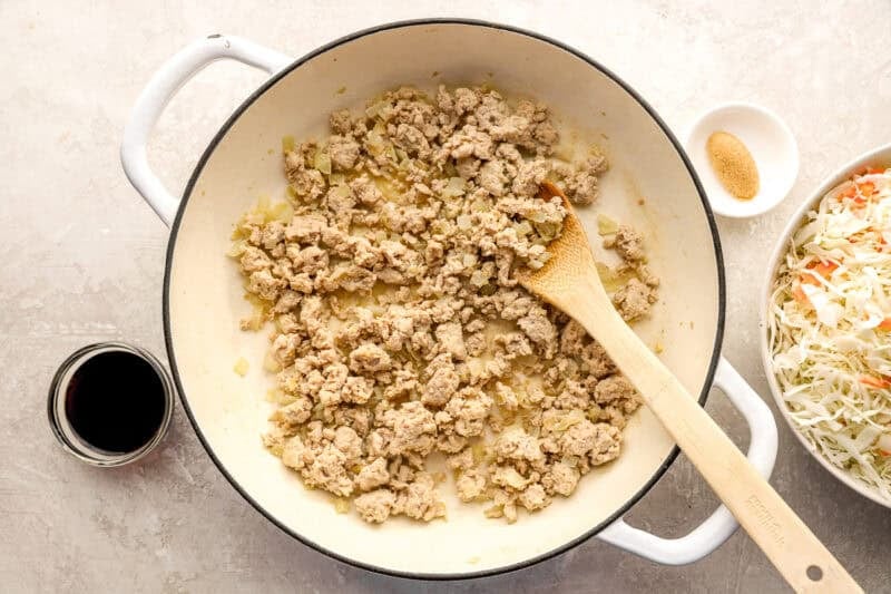 Browning ground chicken in a skillet.