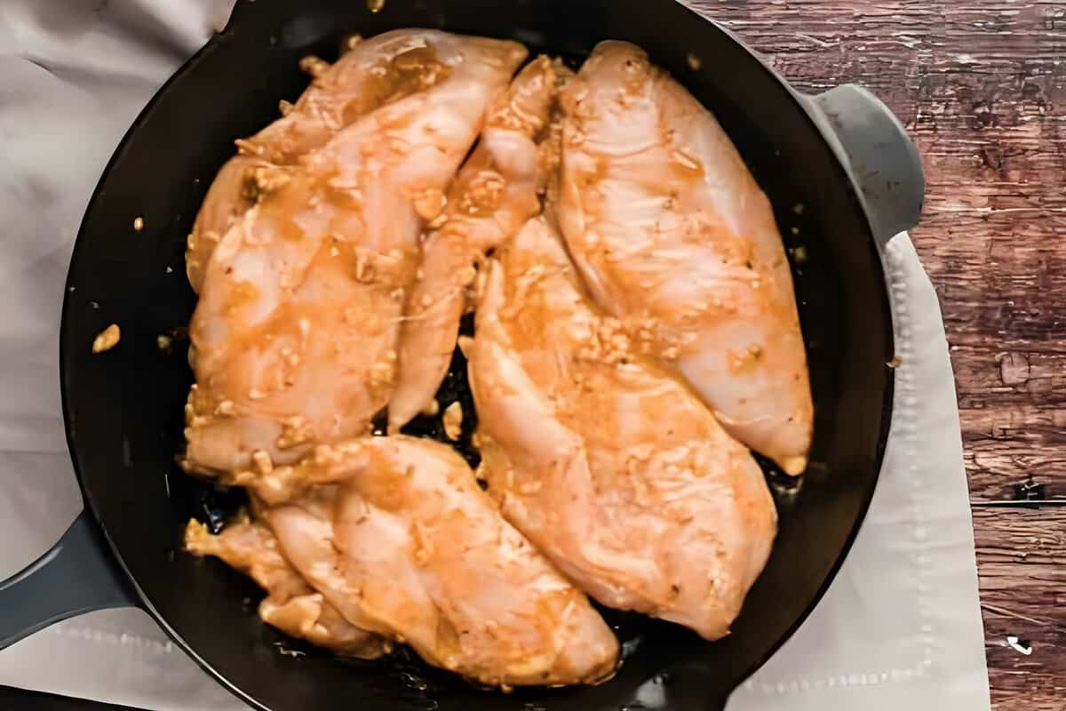 Marinated chicken cooking in a skillet.