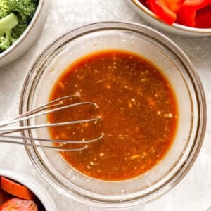 Stir fry sauce being whisked together in a glass bowl.