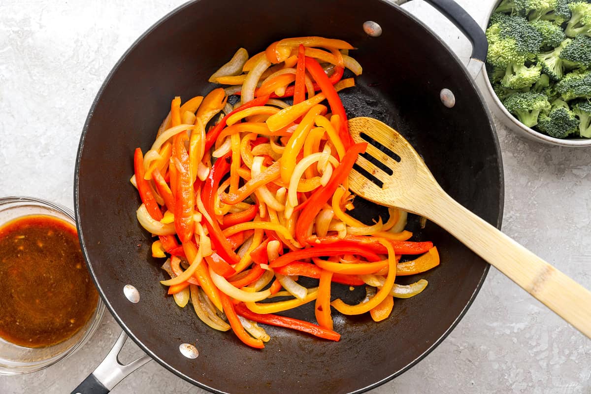 Onions and bell peppers being cooked in a skillet.