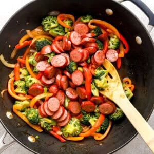 Sausage being stirred into the vegetables.