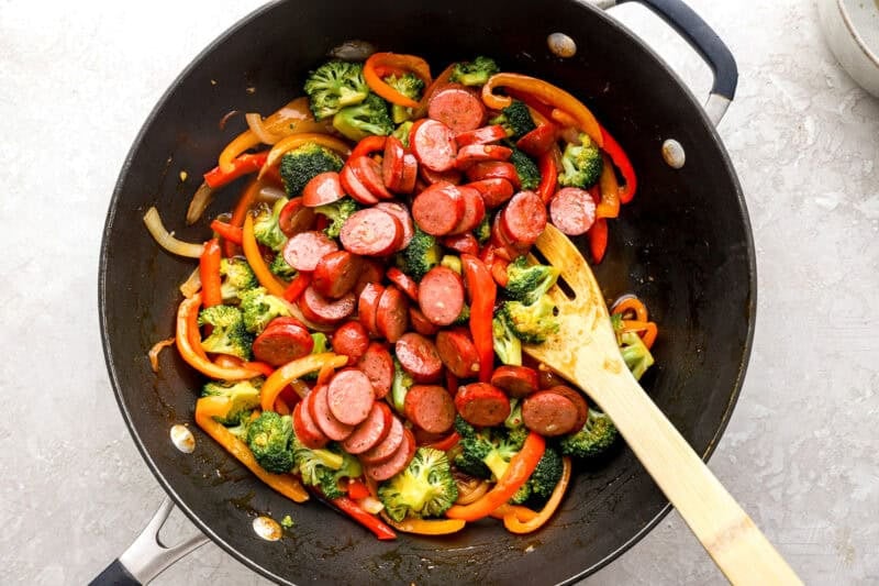 Sausage being stirred into the vegetables.