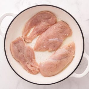 Seasoned chicken breasts in a skillet.