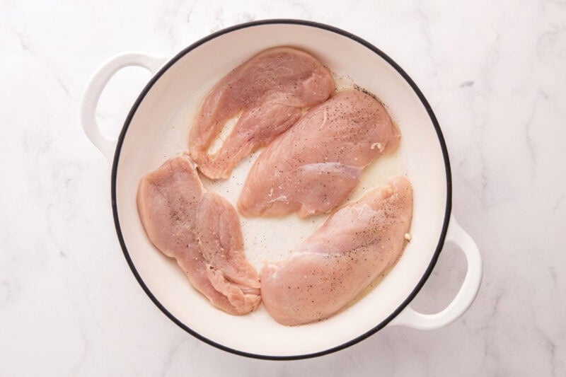 Seasoned chicken breasts in a skillet.