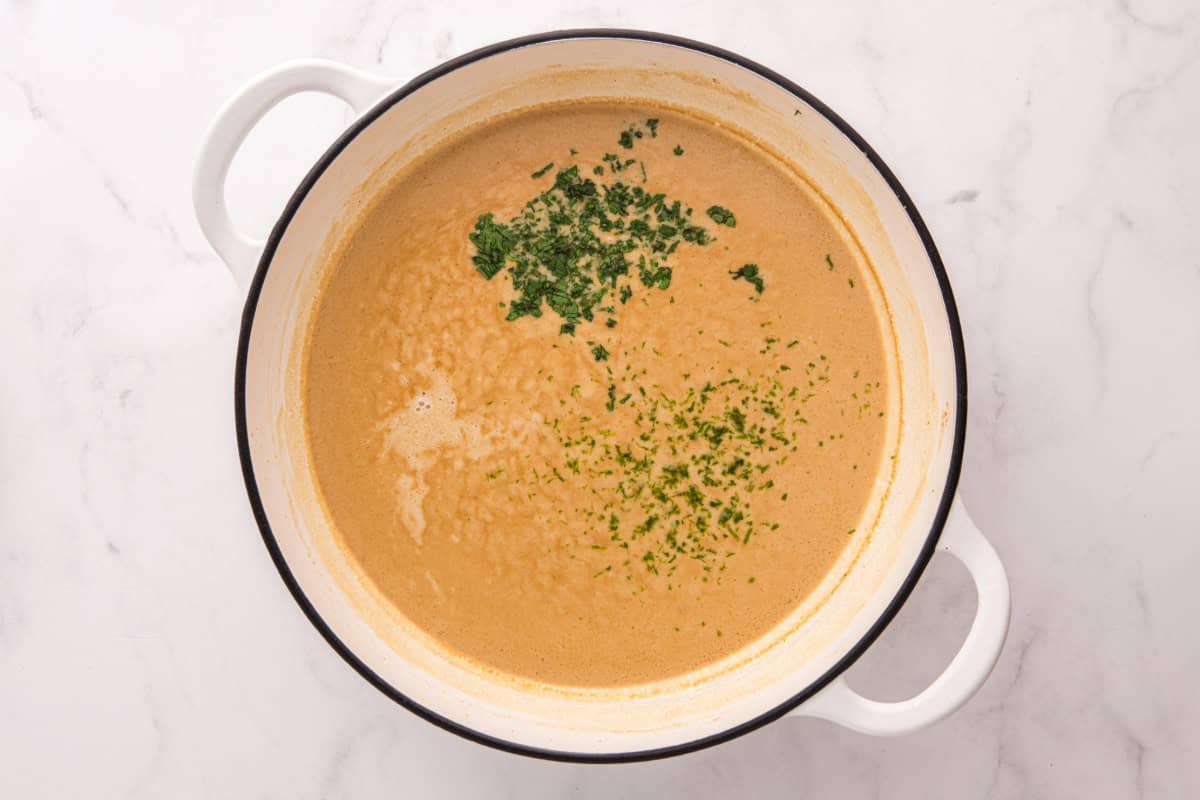 Coconut milk sauce with added lime and cilantro, cooking in a pot.