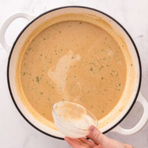 Cornstarch slurry being poured into the sauce.