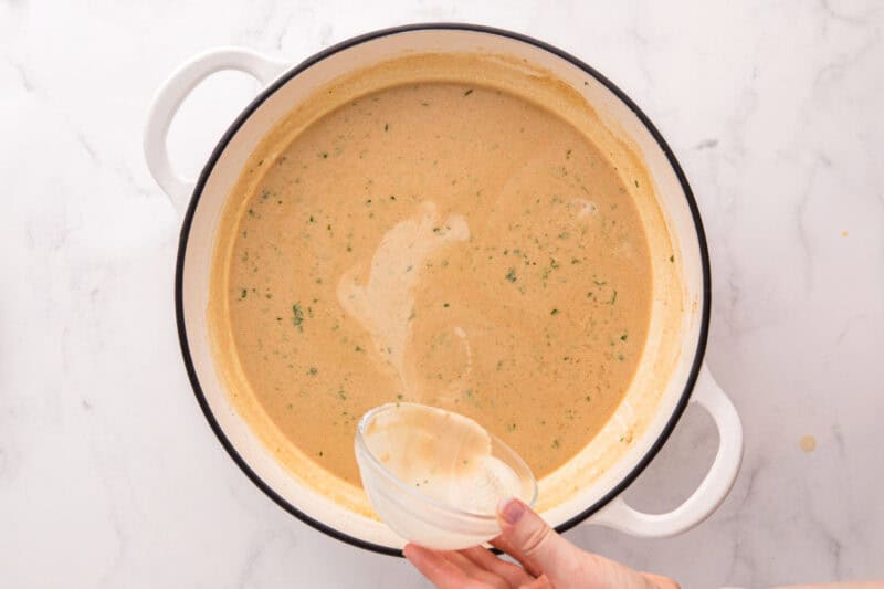 Cornstarch slurry being poured into the sauce.