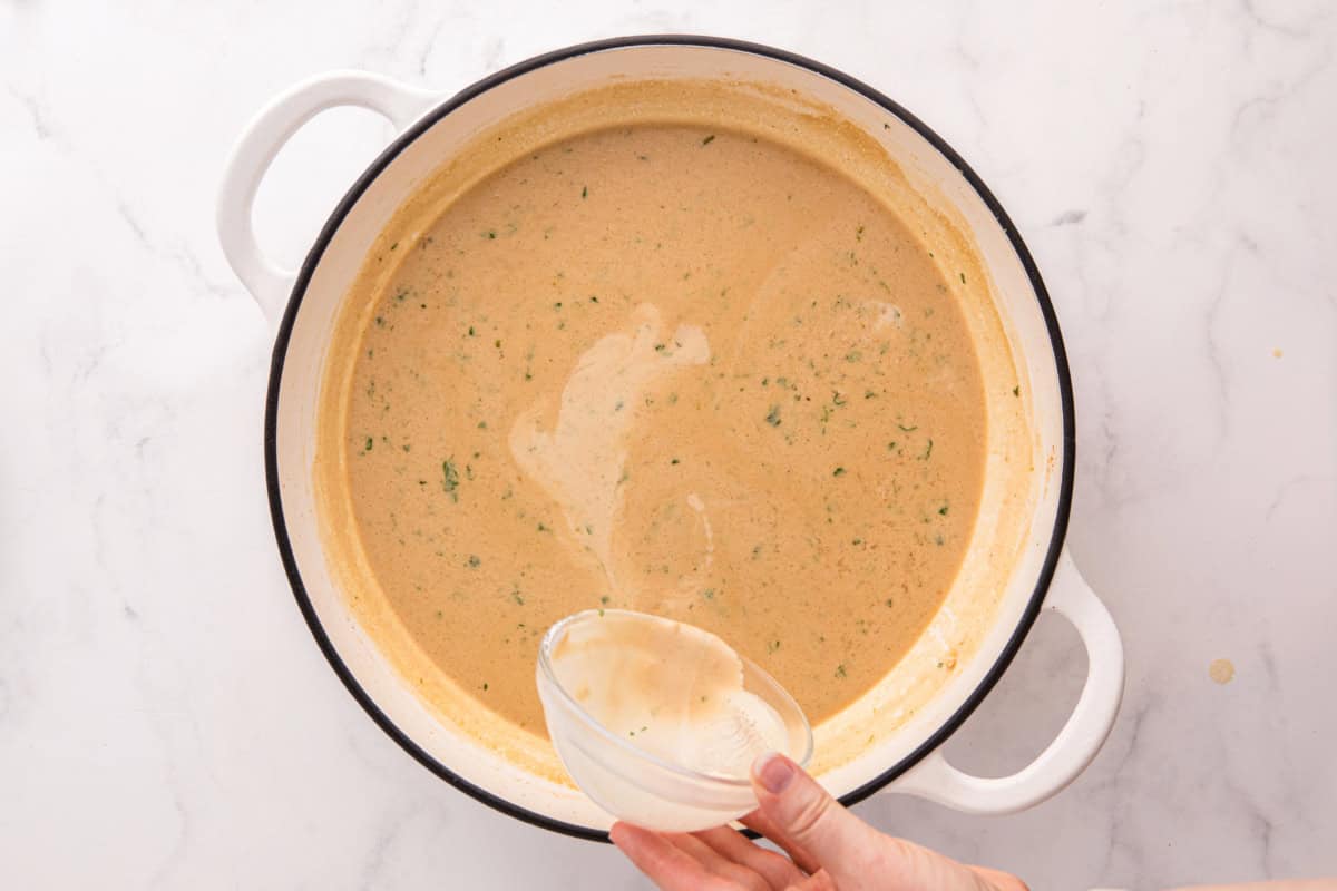 Cornstarch slurry being poured into the sauce.