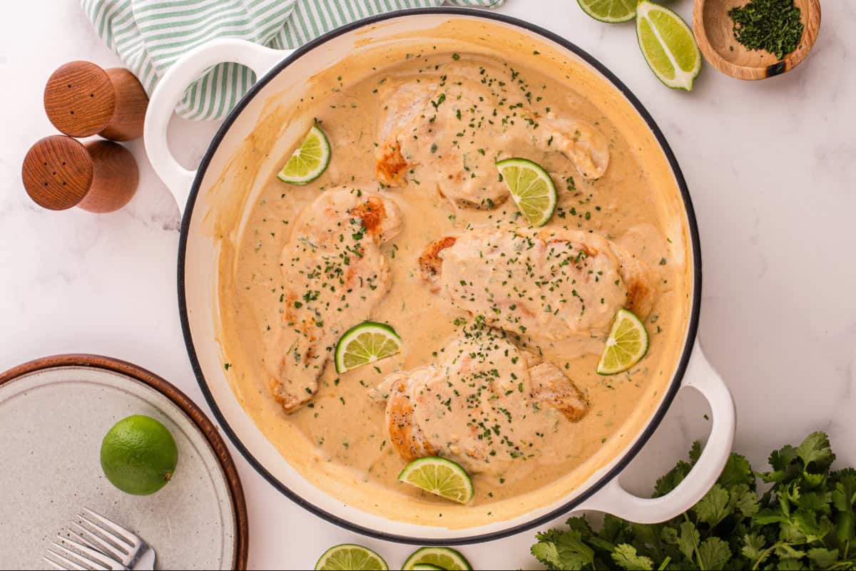 Coconut lime chicken in a skillet of coconut milk sauce.