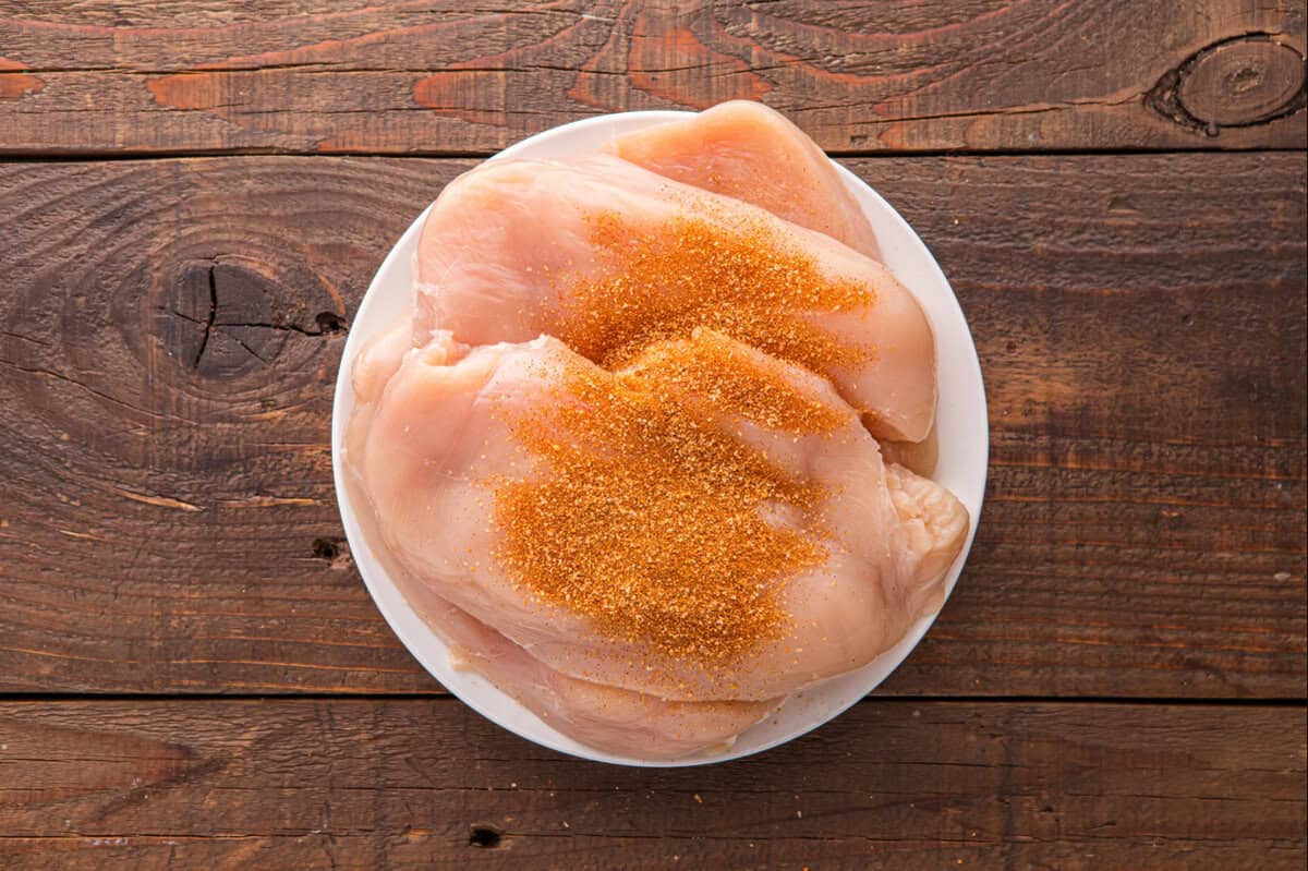 Raw chicken breasts coated with BBQ spice rub.