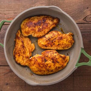 Browned chicken breasts in a skillet.