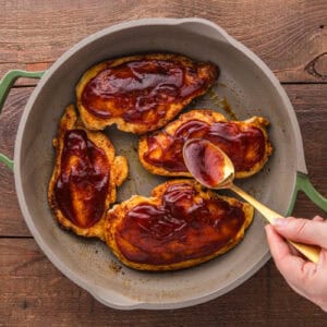 Barbecue sauce being spread on chicken breasts.