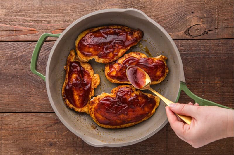 Barbecue sauce being spread on chicken breasts.
