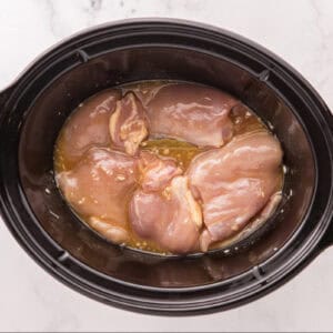 Raw chicken thighs in the slow cooker.