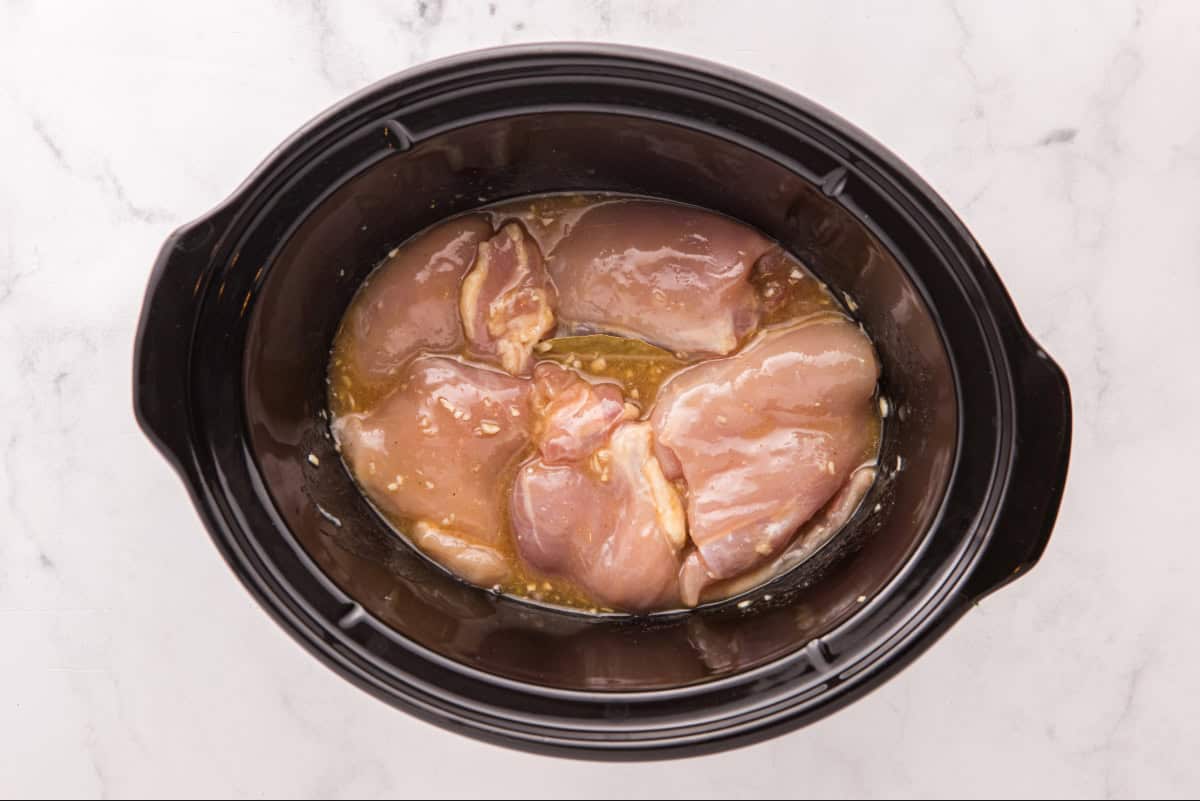 Raw chicken thighs in the slow cooker.